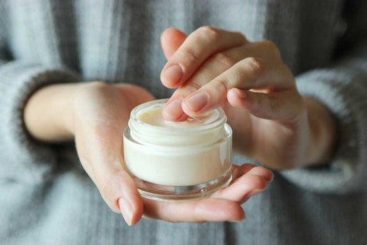 Eine Frau entnimmt Creme für die Hautpflege.