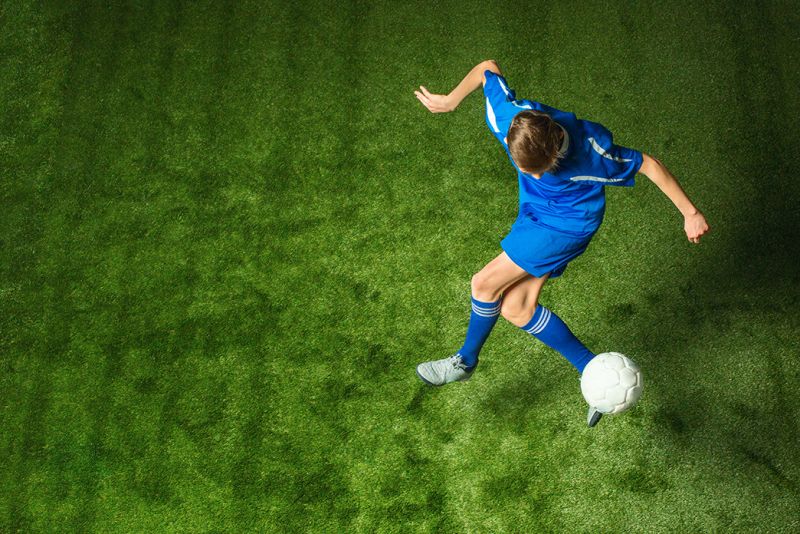 Fussballer spielt mit Ball auf Rasen ohne Verletzungen.
