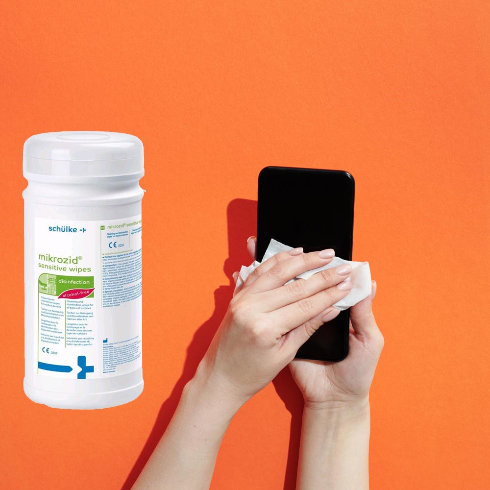 Hände reinigen ein Smartphone mit Mikrozid Sensitive Desinfektionstuch aus der Dose