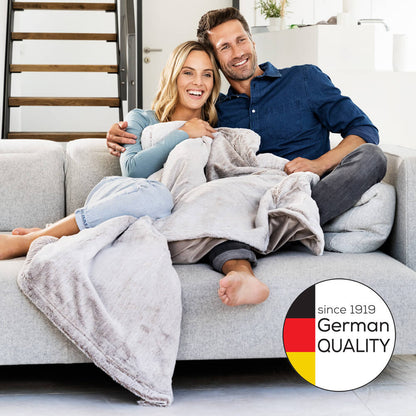 Graue Heizdecke mit gefalteter Decke, auf Sofa ausgebreitet