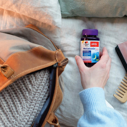 Doppelherz aktiv Melatonin-Weichgummis-Flasche in Hand mit violettem Deckel