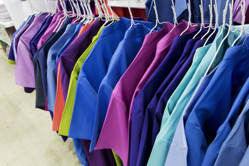 Colourful surgery wear hangs on hangers.