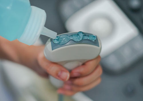 Blauwe ultrasone gel wordt op een ultrasoon apparaat aangebracht