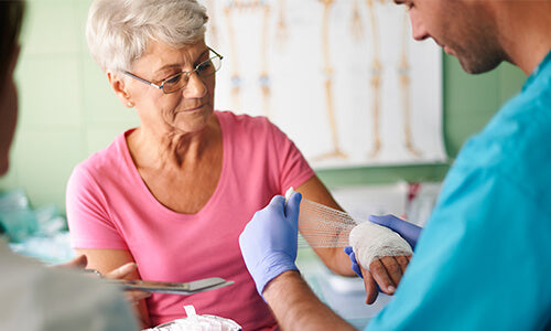 A person applying a zinc paste bandage to an elderly woman
